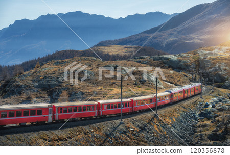 Red modern train is winding through the swiss alps on a sunny day 120356878
