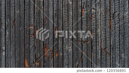 Burnt vertical wood planks texture on a bright sunny day.  120356891