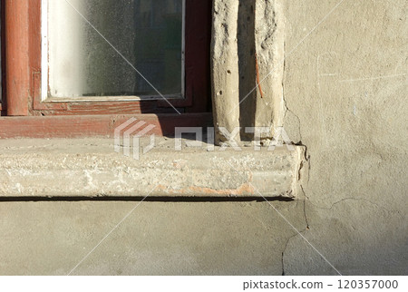 Corner wooden window red frame and glass. Sill and wall texture gray cement plaster with cracks 120357000