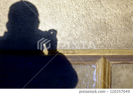 Silhouette shadow of a photographer guy on wall with textured plaster and gold paint in recesses 120357049