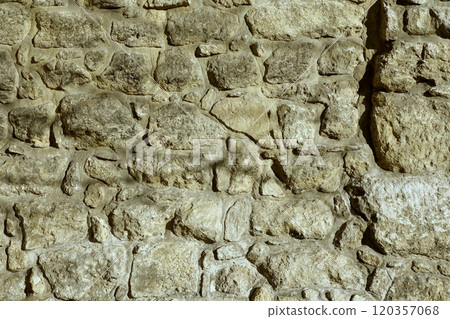 Ancient Stone Wall Consisting of Textured Boulders With Natural Light Casting Shadows 120357068