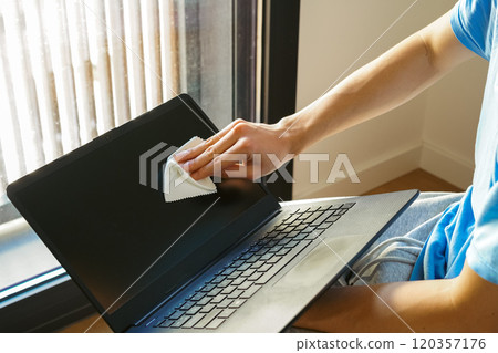 A young man cleaning a computer monitor with a cleaning cloth A young man cleaning a computer monitor with a cleaning cloth 120357176