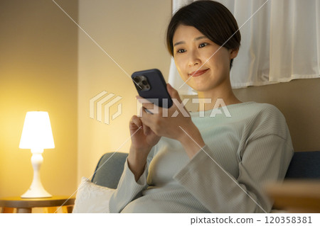 Young woman looking at her smartphone at night 120358381