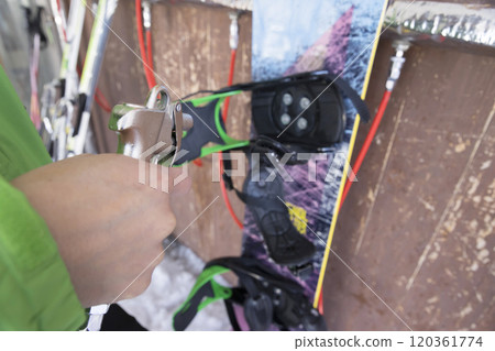 A man using an air gun to remove snow from a snowboard - Snowboarding image 120361774