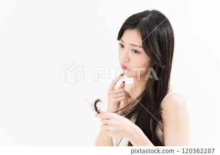 A young woman who is concerned about split ends with hair care A young woman who is concerned about split ends with hair care 120362287
