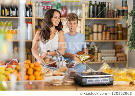 Adolescence boy with mother choose consider snacks in shop 120362968