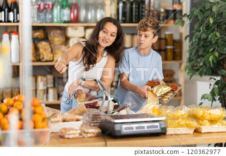 Adolescence boy with mother choose consider snacks in shop 120362977