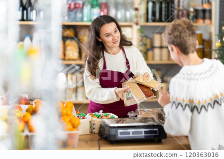 Woman seller serves teen boy customer, demonstrates various versions of nougat, Christmas sweets. Woman seller serves teen boy customer, demonstrates various versions of nougat, Christmas sweets. 120363016