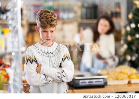 Boy quarrels with mom in decorated grocery store 120363017