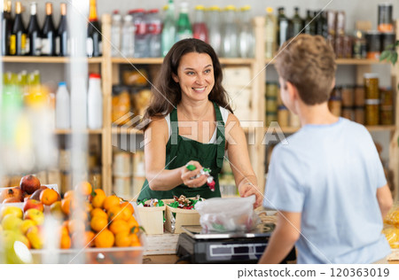 Woman sells sweets to teen boy, puts them on scale and weighs sweets 120363019