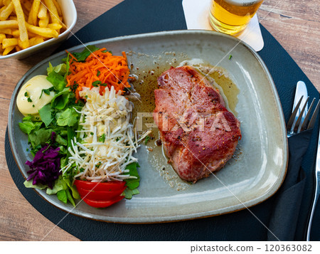 Piece of fried pork in sauce. Served with finely chopped carrots, lettuce, tomatoes and other vegetables. Belgian cuisine Piece of fried pork in sauce. Served with finely chopped carrots, lettuce, tomatoes and other vegetables. Belgian cuisine 120363082