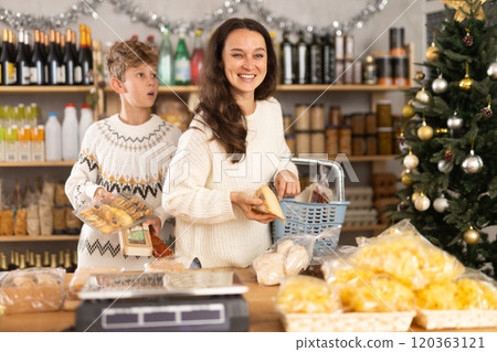 Adolescence boy with mother choose consider snacks in shop on eve of New Year 120363121