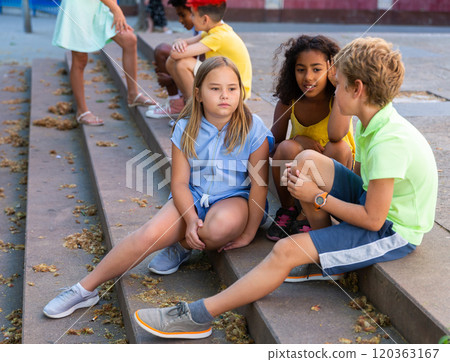 Positive tweenagers friendly blabbing while sitting on steps outdoors Positive tweenagers friendly blabbing while sitting on steps outdoors 120363167