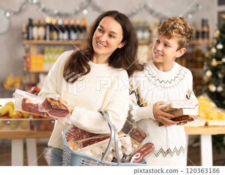 Adolescence boy with mother choose consider snacks in shop on eve of New Year 120363186