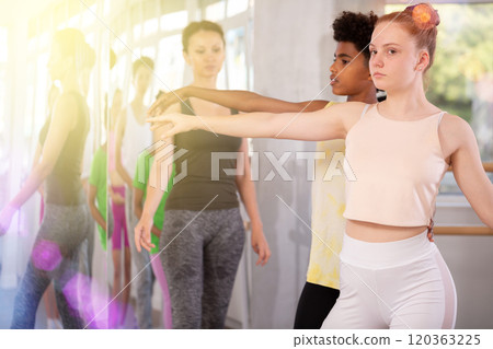 Teenage girl training in pair with dark-skinned boy in ballet studio Teenage girl training in pair with dark-skinned boy in ballet studio 120363225