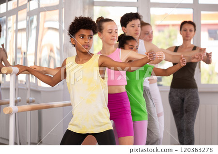 African American teen boy mastering demi plie at barre at ballet class 120363278