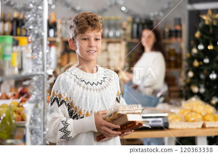 Teenage boy choosing and buying different candies and sweets for Christmas celebration Teenage boy choosing and buying different candies and sweets for Christmas celebration 120363338