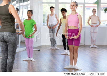 Teenage girl practicing basic ballet moves at group class 120363401