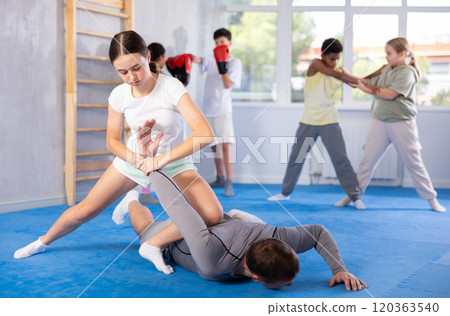Teenage girl practicing painful armlock in sparring with instructor at self defence training Teenage girl practicing painful armlock in sparring with instructor at self defence training 120363540
