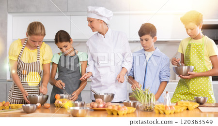 Adult woman cook teaches to cook group of children Adult woman cook teaches to cook group of children 120363549