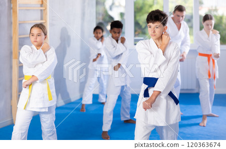 Determined tween boy practicing punches during group martial arts workout Determined tween boy practicing punches during group martial arts workout 120363674