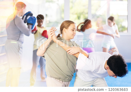 Tween girl practicing painful armlock in training bout with boy during self defence course Tween girl practicing painful armlock in training bout with boy during self defence course 120363683