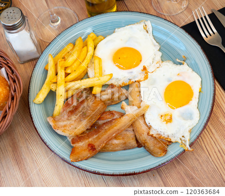 Delicious breakfast - scrambled eggs with bacon and french fries closeup Delicious breakfast - scrambled eggs with bacon and french fries closeup 120363684