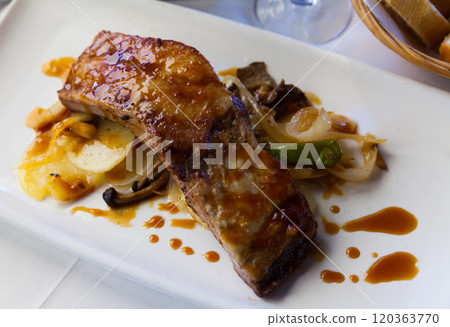 Baked under sauce tasty pork ribs at plate with mushrooms 120363770