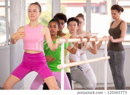 Woman teacher corrects teenagers in plie movement 120363773