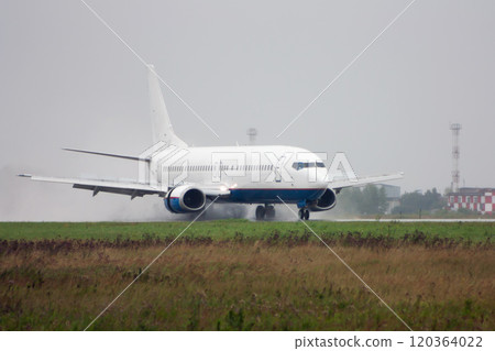 Passenger airplane heading on the runway with extended spoilers in heavy rain Passenger airplane heading on the runway with extended spoilers in heavy rain 120364022