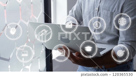 Image of icons over african american businessman using laptop in office Image of icons over african american businessman using laptop in office 120365530