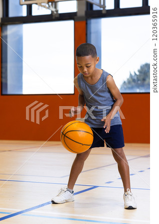 Dribbling basketball, young boy practicing in school gym, focusing on skills Dribbling basketball, young boy practicing in school gym, focusing on skills 120365916