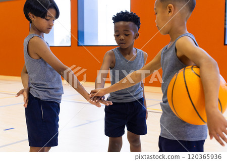 In school gym, boys in sportswear huddling with basketball, preparing for game 120365936