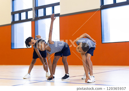 In school gym, kids exercising and stretching together during physical education class 120365937
