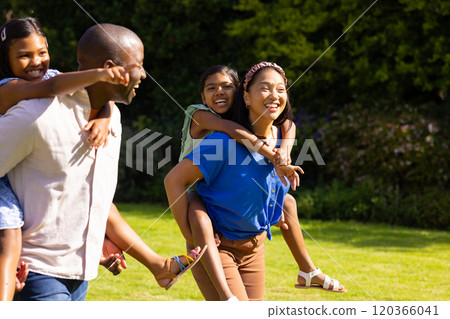 family giving piggyback rides to daughters, enjoying family time outdoors family giving piggyback rides to daughters, enjoying family time outdoors 120366041