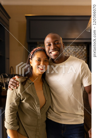 Smiling multiracial couple standing together in kitchen, enjoying time at home Smiling multiracial couple standing together in kitchen, enjoying time at home 120366070