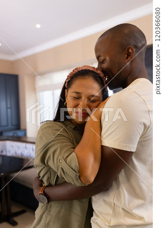 Embracing warmly, multiracial couple enjoying tender moment together at home Embracing warmly, multiracial couple enjoying tender moment together at home 120366080