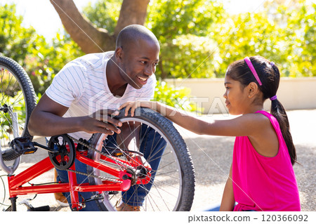 Fixing bicycle, father teaching daughter how to repair bike in outdoor setting Fixing bicycle, father teaching daughter how to repair bike in outdoor setting 120366092