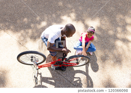 Fixing bicycle, father teaching daughter how to repair bike outdoors Fixing bicycle, father teaching daughter how to repair bike outdoors 120366098
