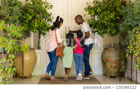 Family of four entering home, father unlocking door, children waiting eagerly 120366122