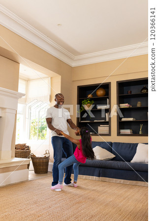 Father playing with daughter in living room, holding hands and smiling Father playing with daughter in living room, holding hands and smiling 120366141