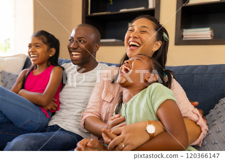 Laughing together, happy family of four sitting on couch at home Laughing together, happy family of four sitting on couch at home 120366147