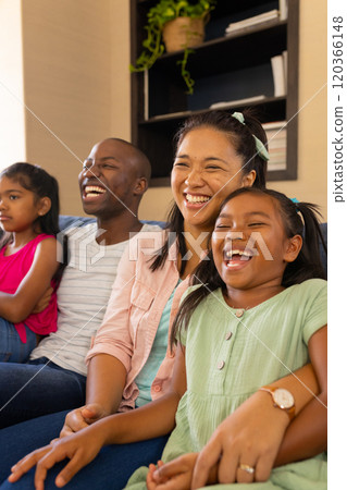 Smiling family of four sitting on couch, enjoying quality time together at home 120366148