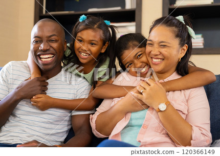 Smiling family of four sitting on couch, enjoying quality time together 120366149