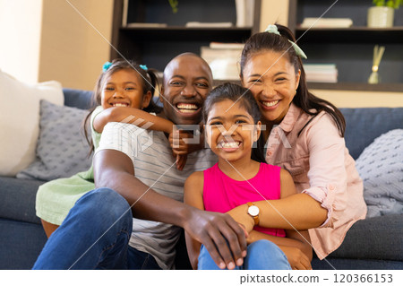 Smiling family of four sitting on couch, enjoying quality time together at home 120366153