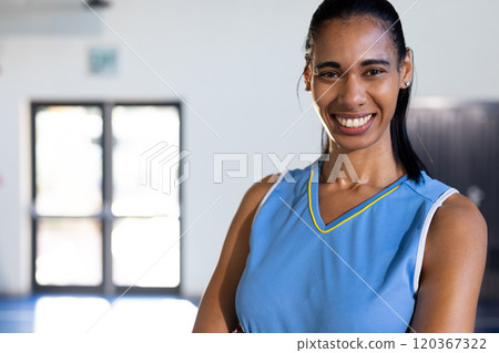 Smiling female basketball player in blue jersey posing confidently in gym 120367322
