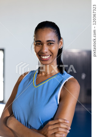 Smiling female basketball player in blue jersey standing with arms crossed Smiling female basketball player in blue jersey standing with arms crossed 120367323