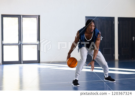 Dribbling basketball, african american man on indoor court, focusing on skills, copy space 120367324