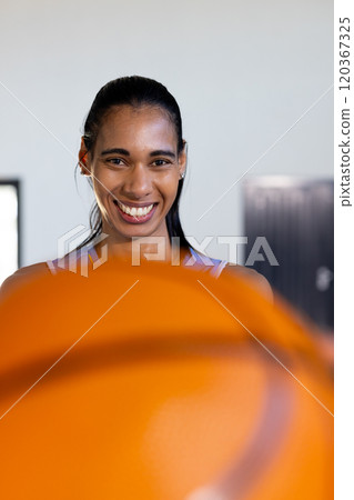 Smiling woman holding basketball, ready for game in sports gym 120367325