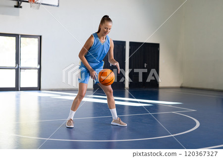 Dribbling basketball, woman practicing on indoor court, focusing on skills 120367327